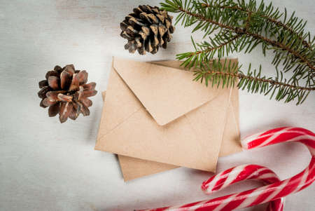 Christmas mail, envelopes with letters on a light wooden table next to a Christmas tree branches,...