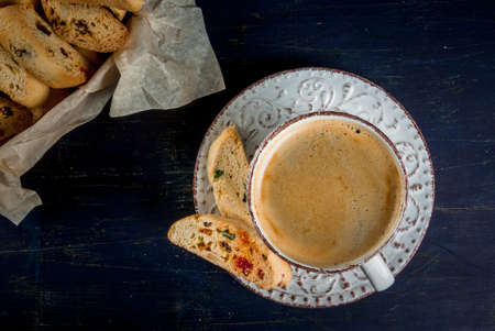 Traditional Christmas baking biscotti cantucci or in a basket on a dark blue wooden table, next to the branches of a Christmas tree and a cup of coffee, top view, copy spaceの写真素材