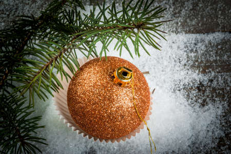 Christmas decorations on a wooden table: Gold Christmas ball in cake tins next to the branches of Christmas treeの写真素材