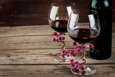 Bottle of wine and two glasses of wine, decorated with artificial branch of winter berries. The festive mood, Valentine's Day, Thanksgiving or Christmas. Copy spaceの写真素材