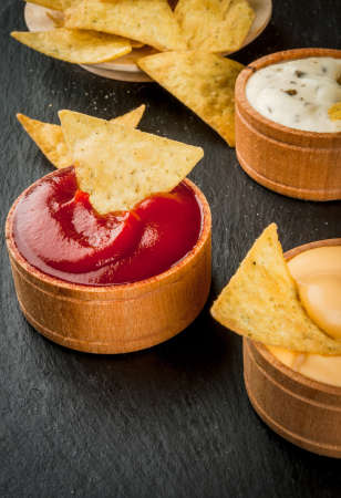 Snack for party, chips, nachos with sauces: tomato (ketchup), cheese and mayonnaise (tartar), copy spaceの写真素材