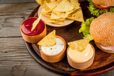 Selection of different food for a party: chips, nachos with sauces (tomato, cheese and mayonnaise...