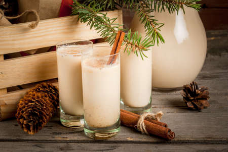 Traditional Christmas alcoholic cocktail - Irish Cream, Cola de mono (monkey tail), decorated with cinnamon. Against the background of Christmas decorations on a wooden table. Close viewの写真素材