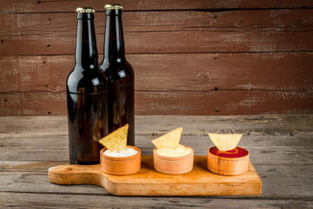 Snack for party, chips, nachos with sauces: tomato (ketchup), cheese and mayonnaise (tartar), with two bottle of beercopy spaceの写真素材