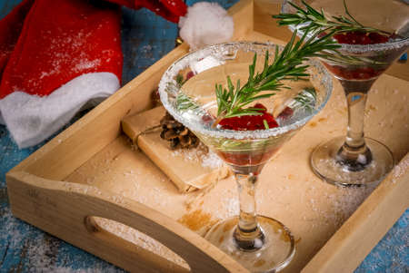 Christmas refreshing alcoholic drink with cranberries and rosemary on wooden background, with gift and decorationsの写真素材