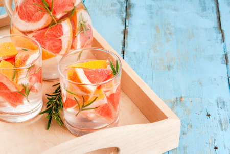 Refreshing summer detox cocktail of grapefruit and rosemary, on wooden rustic table, copy space