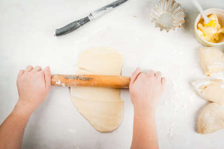 Cooking fashionable baking - scones cruffins (puffmaffin), a mixture of a croissant and a muffin. The girl rolls the dough, hands in the shotの写真素材
