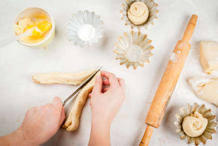 Cooking fashionable baking - scones cruffins (puffmaffin), a mixture of a croissant and a muffin. The girl cuts dough, hands in the shotの写真素材