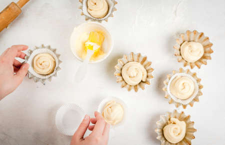 Cooking fashionable baking - scones cruffins (puffmaffin), a mixture of a croissant and a muffin. Girl lays in a scones tins, hands in the shotの写真素材