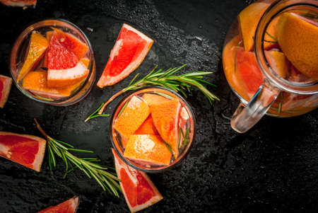 Ingredients for a refreshing summer detox cocktail of grapefruit and rosemary on black backgroundの写真素材
