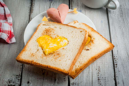 Idea for the celebration of Valentine's day: breakfast - toast with scrambled eggs in the form of hearts, sausages and cheese in the form of hearts and aromatic coffee with cinnamon, copy spaceの写真素材