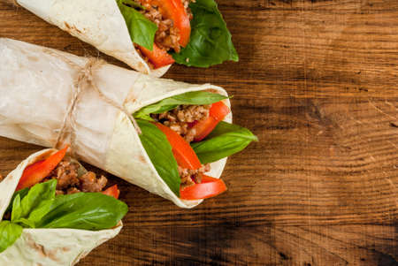 Healthy lunch snack. Sandwiches twisted roll Tortilla with beef and vegetables a wooden cutting board on blue wooden rustic table, copy space, top viewの写真素材