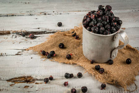 Rustic old mug with frozen blueberries and currants, on white wooden tableの写真素材