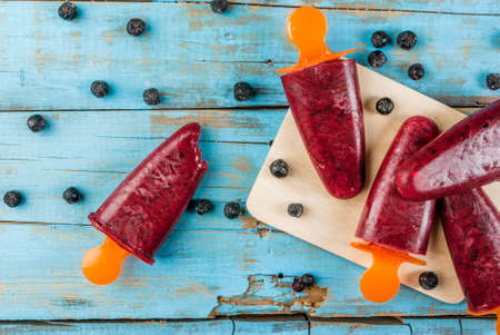 Delicious home-made popsicles of black currant. On a wooden table, top view, copy spaceの写真素材