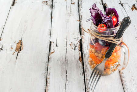 Fresh vegetable salad with chickpeas in a mason jar on a rustic wooden tableの写真素材