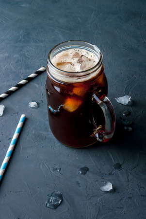 Iced coffee in a Mason Jar with straws and ice om the background. copy spaceの写真素材