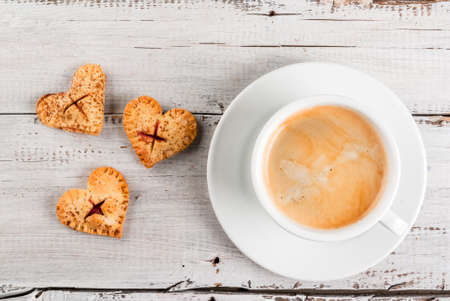 Idea for the celebration of Valentine's Day: one bite  cherry pies in the form of hearts, cup of coffee, top viewの写真素材