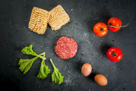 Ingredients for cooking ramen burger: raw minced beef for burgers, uncooked noodles ramen, eggs, tomatoes and lettuceの写真素材