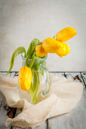 Bouquet of spring flowers tulips in a jug on a white rustic table, vertical, copy spaceの写真素材