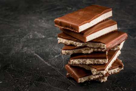 Stack of pieces of chocolate filled with white nougat on a dark stone table, copy spaceの写真素材