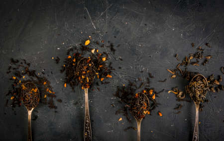 Selection of fragrant teas with dried fruits and spices in teaspoons, that a dark background, top view, copy spaceの写真素材