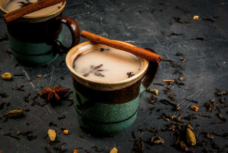 Traditional Indian masala chai tea in ceramic cups, stone table, with spices, copy spaceの写真素材