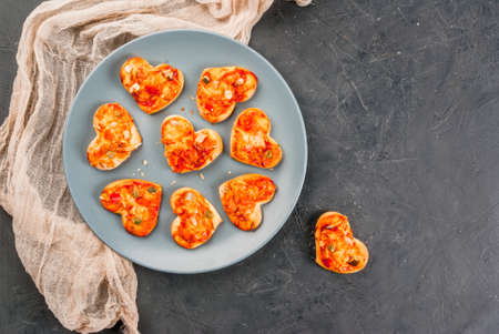Romantic foods for Valentine's Day. Miniature pizza at one bite, cheese and fresh vegetables, close...