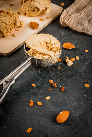 Home made caramel nut ice cream spoon and balls on the kitchen board, on a stone gray table, close...
