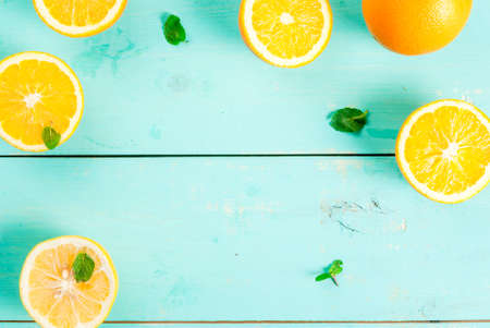 Background. Blue wooden table with oranges halves and mint leaves, spread out in a frame, top view,...