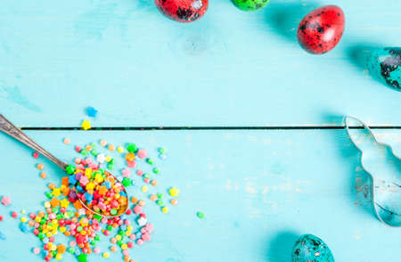 Easter background with cookie cutter in shape of symbol of Easter - Bunny, colorful eggs and sugar sprinkles for cookies and cakes, top view, copy spaceの写真素材