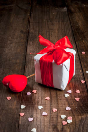 Gifts and decorations in the form of hearts for Valentine's Day, on a wooden table with a scattering of sprinkling sugar in the shape of hearts, copy space, verticalの写真素材