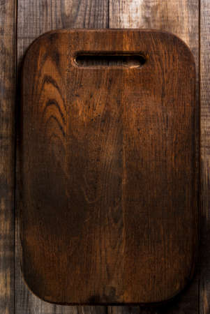 Dark wooden table made of planks (pine) with a cutting boardの写真素材