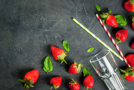 Ingredients for strawberry smoothie on the table glass, striped straws, strawberry and mint, On the gray stone or concrete background. top view, copy spaceの写真素材