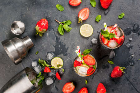 Summer refreshing mojito cocktail with strawberry, mint and lime, on a dark gray stone (concrete) table with shaker for whipping drinks, top viewの写真素材