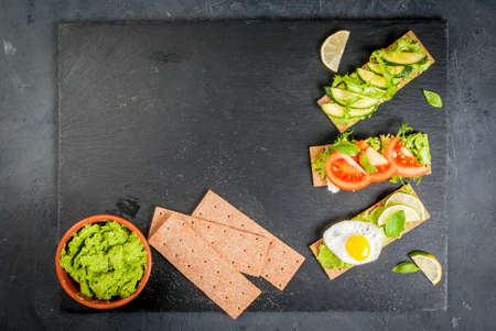 Healthy Eating, Diet sandwiches on gluten-free loaves - with guacamole, fresh vegetables (tomato, cucumber), egg, lime, lettuce and basil, On a stone (concrete) gray table, top view, copy spaceの写真素材