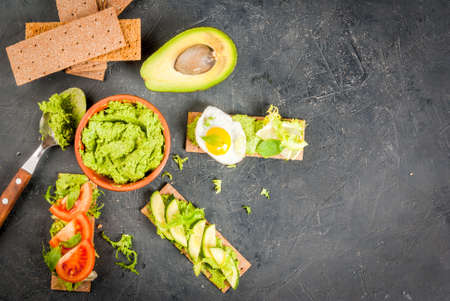 Healthy Eating, Diet sandwiches on gluten-free loaves - with guacamole, fresh vegetables (tomato, cucumber), egg, lime, lettuce and basil, On a stone (concrete) gray table, top view, copy spaceの写真素材