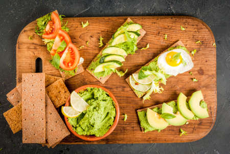 Healthy Eating, Diet sandwiches on gluten-free loaves - with guacamole, fresh vegetables (tomato, cucumber), egg, lime, lettuce and basil, On a stone (concrete) gray table, top view, copy spaceの写真素材