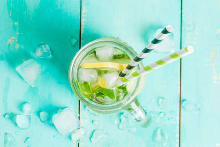 Refreshing summer drink - detox cocktail of mint, cucumber and lemon. On a light blue wooden table, bright sunlight, copy space, top viewの写真素材