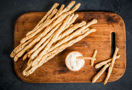 Traditional Italian snack, bread - grissini. On a dark stone table, top view, copy spaceの写真素材
