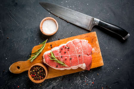 Fresh uncooked roastbeef on a cutting board with salt, pepper and rosemary, with knife for cooking. Top viewの写真素材