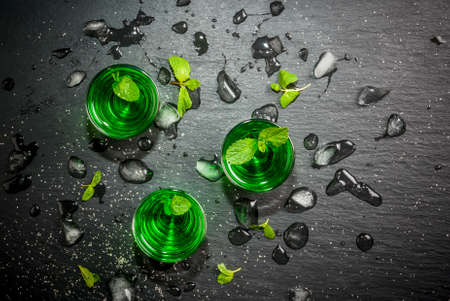 Sweet refreshing mint liqueur, with ice and mint leaves on the slate tray to feed on gray concrete stone table, top view, copy spaceの写真素材