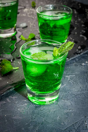Sweet refreshing mint liqueur, with ice and mint leaves on the slate tray to feed on gray concrete stone table, close viewの写真素材