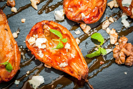 Fresh summer salad - grilled pears, cheese with blue mold with walnuts and caramel sauce. On the black slate platter. Close viewの写真素材