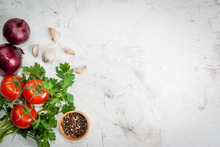 Spices (black pepper, garlic, onion), greens and tomatoes. Ingredients for cooking. On the white stone concrete table top view copy spaceの写真素材