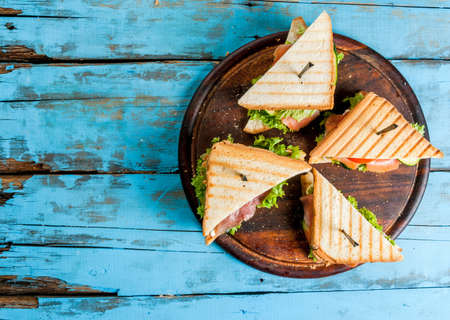 Club sandwiches with fresh lettuce, tomato, cucumber and salmon (trout). On crunchy toast. On blue rustic table, picnic, copy space top viewの写真素材