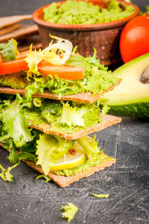 Healthy Eating, Diet sandwiches on gluten-free loaves - with guacamole, fresh vegetables (tomato, cucumber), egg, lime, lettuce and basil, On a stone (concrete) gray table, copy spaceの写真素材
