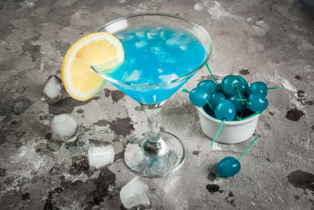 Party, cocktails blue lagoon or blue curacao on a concrete stone table with blue maraschino cherry, copy spaceの写真素材