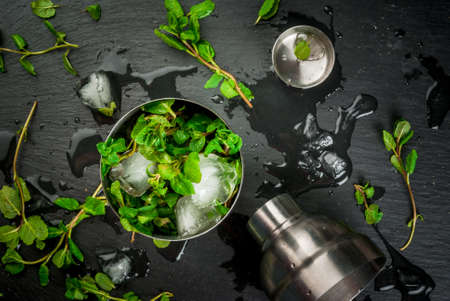 Fresh mint with ice cubes in a shaker. The concept of cooling summer drinks. top view on a black slate board top viewの写真素材