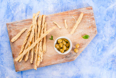 Lunch or snack in the Italian style: grissini breadsticks, oil with olives and basil. On a light...