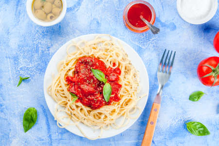 Spaghetti with tomato sauce, olives, tomato and basil on a light blue stone concrete table top view copy spaceの写真素材